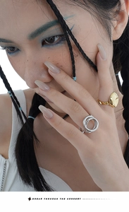 Detail showing minimalist gold and silver intertwined geometric rings on hand