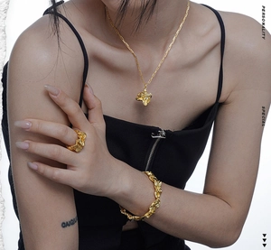 Detailed view of the irregular lava texture on gold necklace, bracelet and ring set