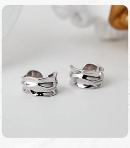 Détail macro d'une bague d'oreille argentée avec texture métal liquide et fini poli