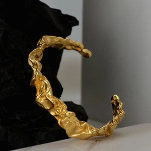 Detalle de brazalete dorado con diseño artístico de textura de lámina arrugada irregular
