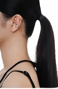 Gros plan de boucles d'oreilles ear cuffs dorées et argentées à texture irrégulière