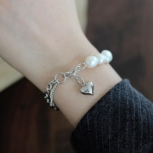 Detalle de pulsera de plata S925 hecha a mano con perlas y colgante de corazón