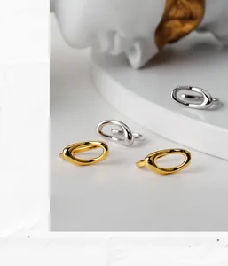 Close-up of irregular hollow geometric silver and gold earrings on a marble base