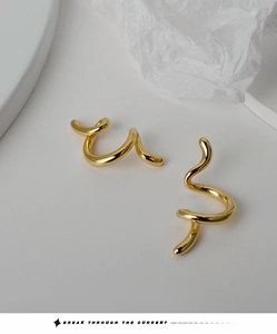 Dettaglio dell'orecchino a clip a spirale dorata con linee fluenti dal design artistico