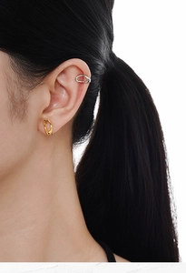 Close-up of minimalist gold oval earring and silver ear cuff on model's ear