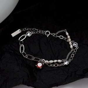 Detalle de pulsera de doble capa de plata con gema roja y perlas blancas