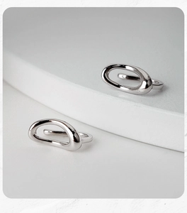 Close-up of minimalist S925 sterling silver oval hollow ear cuffs on a white display