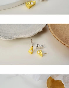 Detail of cheese-shaped pearl earrings in gold and silver finish with realistic texture