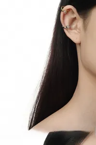 Detail of minimalist gold and silver ear cuffs with pear-shaped zircon on a model ear