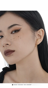 Detailed close-up of a minimalist gold ear cuff with a geometric dual-line cross design