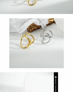 Close-up of dual-line minimalist silver and gold rings on white textured background