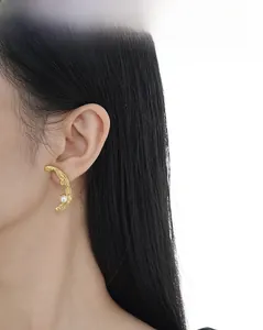 Gros plan de boucles d'oreilles dorées texturées avec perles portées par un mannequin