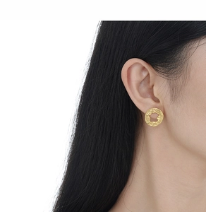 Gros plan détaillé de boucles d'oreilles dorées à texture irrégulière portées par un mannequin