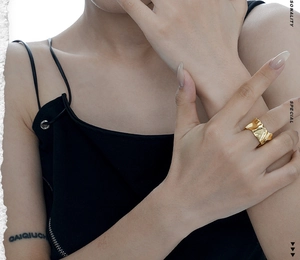 Close-up of golden irregular textured ring with lava surface on model finger