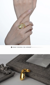 Macro detail of minimalist gold fluid teardrop open ring with a mirror polished finish