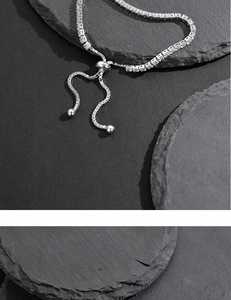 Close-up of adjustable silver tennis bracelet with cubic zirconia on a grey rock