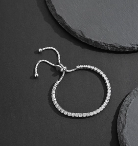 Detail of adjustable silver tennis bracelet with cubic zirconia on stone background