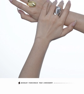Detail of drop-shaped open rings in gold and silver finish with high-polish mirror surface