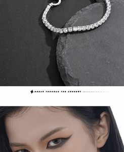 Detailed view of shimmering silver tennis necklace with diamonds on textured rock background