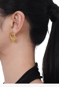 Detailed view of gold textured S925 sterling silver earring on female model ear