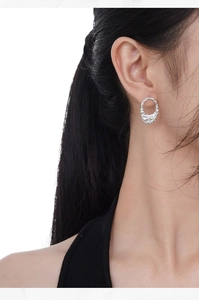 Detailed view of silver S925 earrings with irregular hammered texture on female model