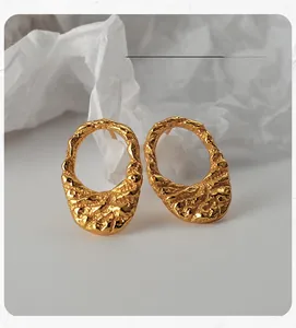 Detail view of gold irregular textured oval earrings with unique lava-like organic finish