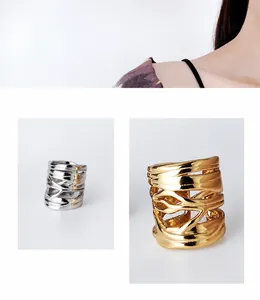 Dettaglio di ear cuff intrecciati irregolari con finitura argento e oro lucido