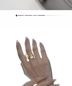 Close-up of a gold geometric ring with a large rectangular zircon on a model hand