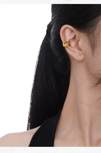 Close-up of minimalist gold-plated concave ear cuff worn on model showing glossy finish