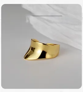 Macro shot of minimalist gold concave wide-band ear cuff with polished mirror finish
