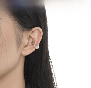 Gros plan du brassard d'oreille géométrique en argent avec perle blanche sur modèle