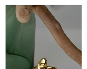 Artistic close-up of irregular golden sculptural ring on a natural wood branch background