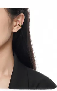 Detailed view of a golden minimalist knotted ear cuff on model with a white background