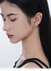 Close-up of model wearing textured S925 sterling silver ear cuffs in gold and silver finish