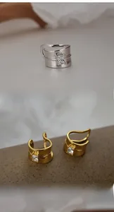 Macro shot of minimalist silver and gold ear cuffs with a rectangular zircon stone