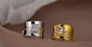 Detail of square zircon inlay on silver and gold textured rings with geometric hollow design