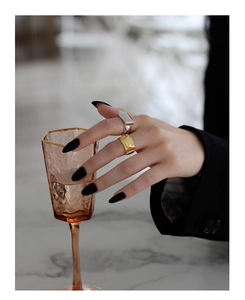 Close-up of minimalist gold and silver wide geometric rings on model with black nails