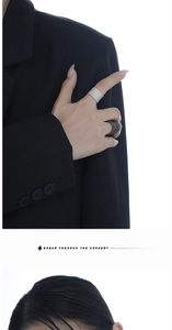 Gros plan de bagues larges texturées en argent et noir mat sur la main d'un mannequin