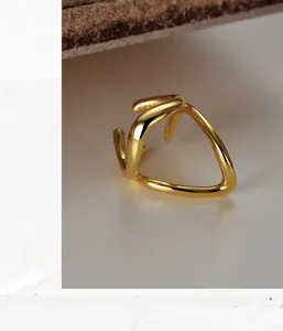 Macro view of a minimalist gold geometric ring featuring an asymmetric curved hollow line