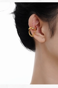 Detailed view of a gold hollow wave cuff earring worn on a female model's ear
