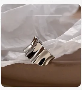 Detail display of a minimalist liquid silver ear cuff with a polished wavy surface