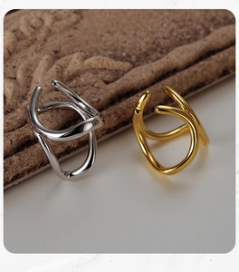 Detail of minimalist wave-shaped interlocking ear clips in polished gold and silver finishes