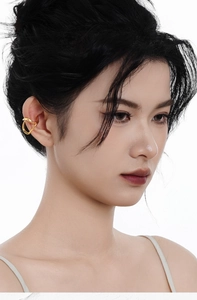 Macro shot of minimalist gold ear cuff with irregular curved lines on female model