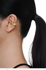 Close-up of a wide wavy gold ear cuff with polished texture worn on the ear cartilage