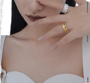Close-up of silver and gold irregular textured open rings with small red gemstones