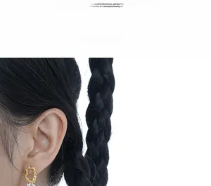 Close-up of golden irregular hollow earrings with elegant white pearl pendants on model