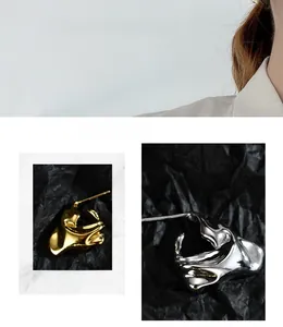 Macro detail of asymmetric irregular lava texture earrings in silver and gold finish