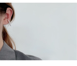 Close-up of minimalist S925 sterling silver irregular drop ear cuff worn on ear