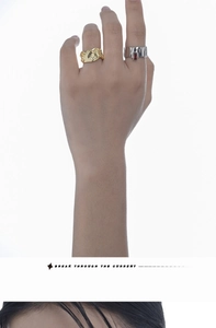 Macro detail of gold irregular wave ring with zircon and silver ring with ruby on finger