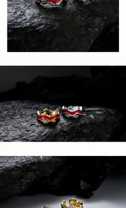Détails de boucles d'oreilles clips en émail rouge et zircons sur roche noire texturée